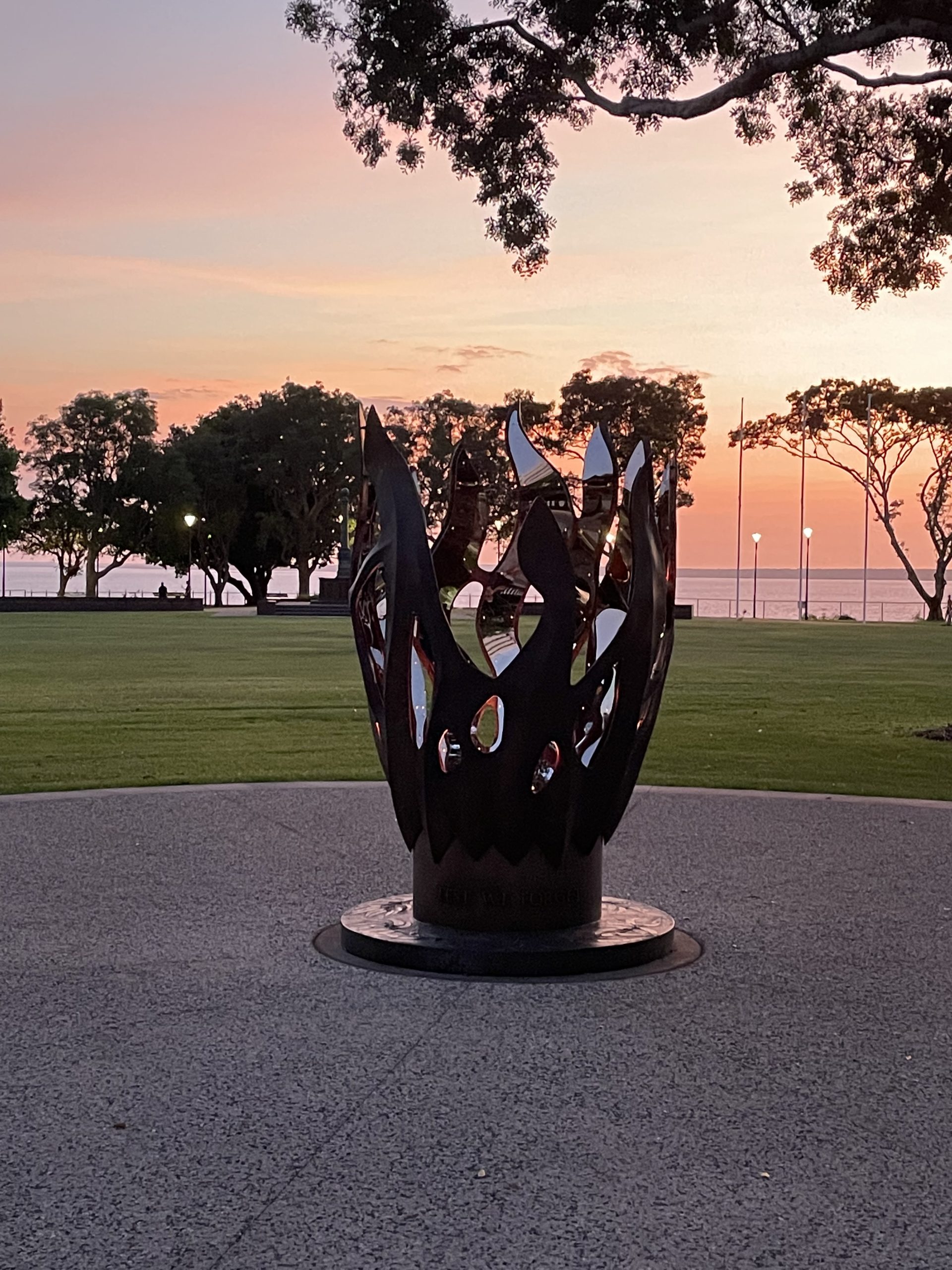 Sunset over a coastal park with a sculptural metal fire vessel